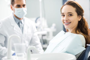 young woman smiling in specialty dentist chair with dental braces in tx