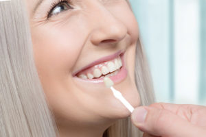 woman smiling as dentist compares dental veneers in TX to her teeth