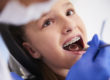 child with braces at dentist learning How to Prevent Teeth Shifting