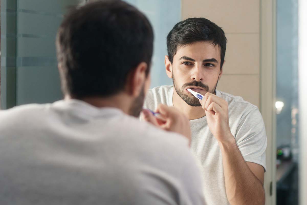 man brushing teeth wondering if that is one of the causes of receding gums