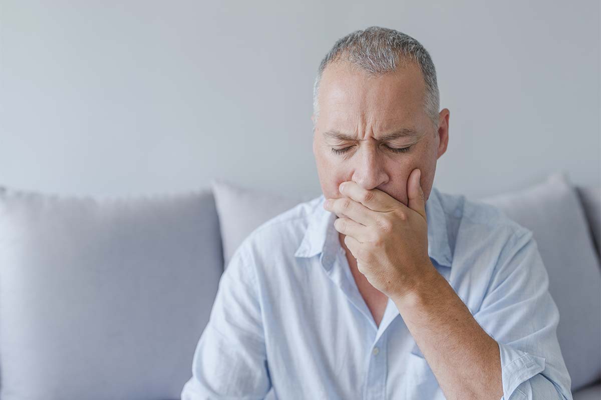 man with hand over mouth needing dental appointment