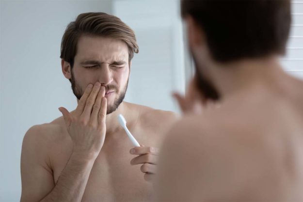 gums (4) man holding jaw due to gums pain