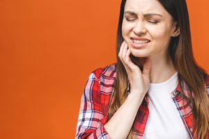 woman struggles with the pain associated with impacted teeth