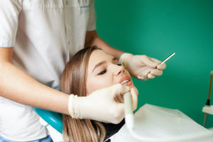 Doctor performs a tooth extraction on a female patient