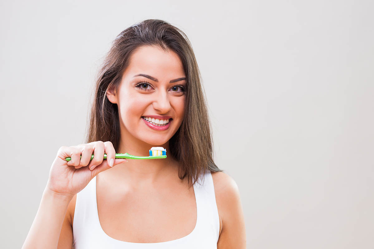 woman brushing her teeth to protect her dental health